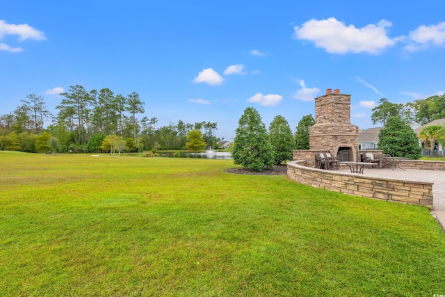 view of yard with an outdoor stone fireplace, a patio, and a water view