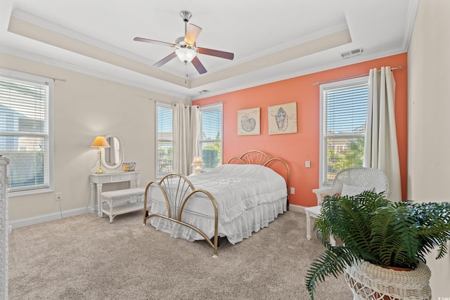 carpeted bedroom with a raised ceiling, multiple windows, and ceiling fan