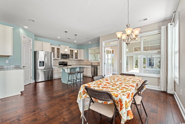 dining room with dark hardwood / wood-style flooring, an inviting chandelier, and sink