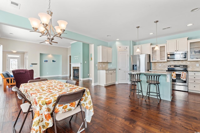 dining room with a tiled fireplace, dark hardwood / wood-style flooring, and ceiling fan with notable chandelier