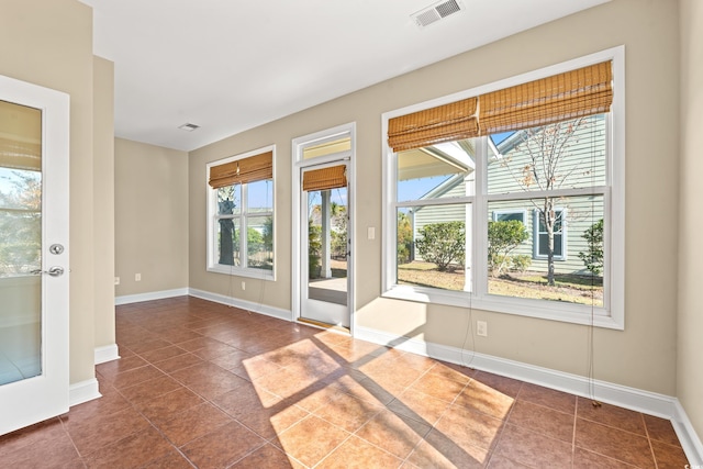 doorway featuring dark tile patterned flooring and plenty of natural light