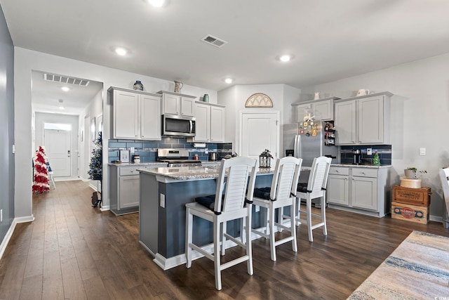 kitchen featuring a kitchen breakfast bar, dark hardwood / wood-style floors, tasteful backsplash, a kitchen island, and stainless steel appliances