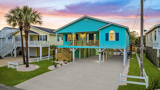 beach home with a carport, a front yard, driveway, and stairway