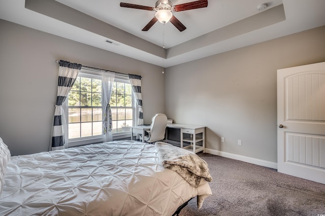 bedroom featuring carpet, a tray ceiling, and ceiling fan