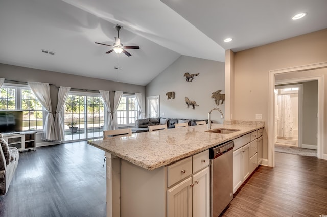 kitchen featuring ceiling fan, sink, light stone counters, stainless steel dishwasher, and lofted ceiling