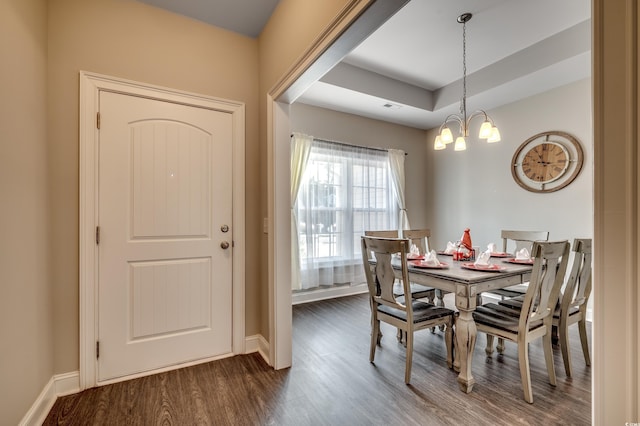 dining room featuring a chandelier, hardwood / wood-style flooring, and a raised ceiling