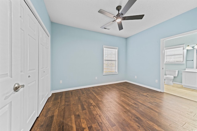 unfurnished bedroom with ceiling fan, dark wood-type flooring, and multiple windows