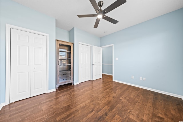 unfurnished bedroom with multiple closets, ceiling fan, and dark wood-type flooring