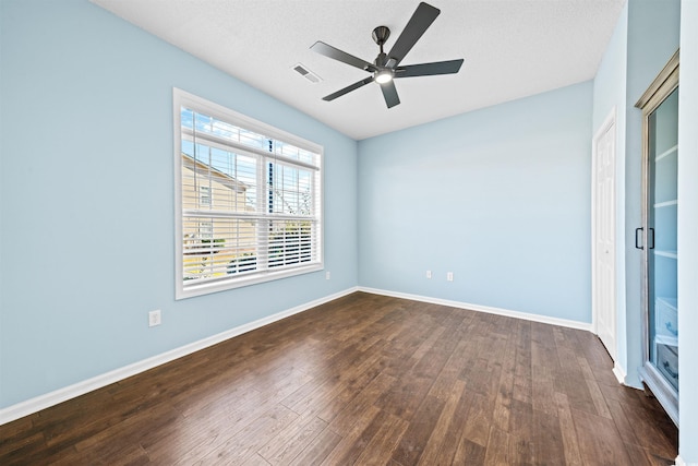 spare room featuring ceiling fan, dark wood-type flooring, and a textured ceiling