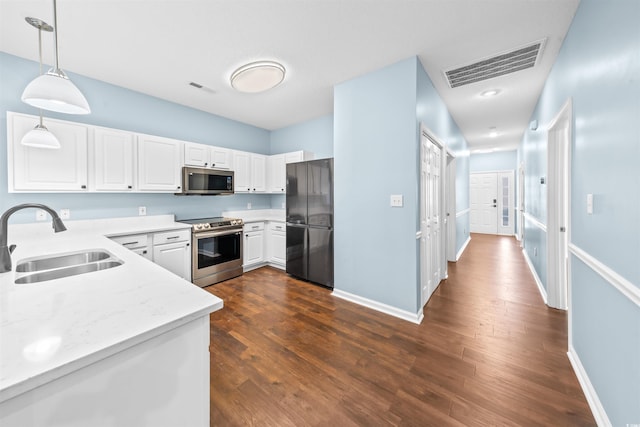 kitchen featuring white cabinets, sink, appliances with stainless steel finishes, decorative light fixtures, and dark hardwood / wood-style flooring