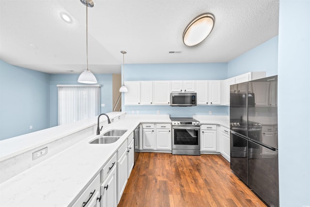 kitchen featuring sink, dark hardwood / wood-style floors, decorative light fixtures, white cabinets, and appliances with stainless steel finishes