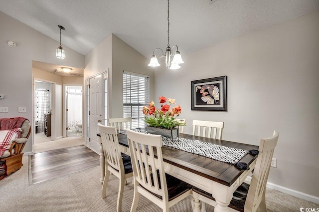 carpeted dining area featuring a textured ceiling, vaulted ceiling, and an inviting chandelier