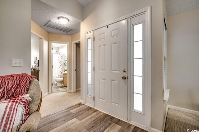 foyer entrance with light wood-type flooring and a textured ceiling