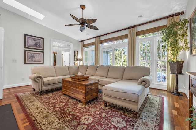 living room featuring ceiling fan, wood-type flooring, and lofted ceiling with skylight