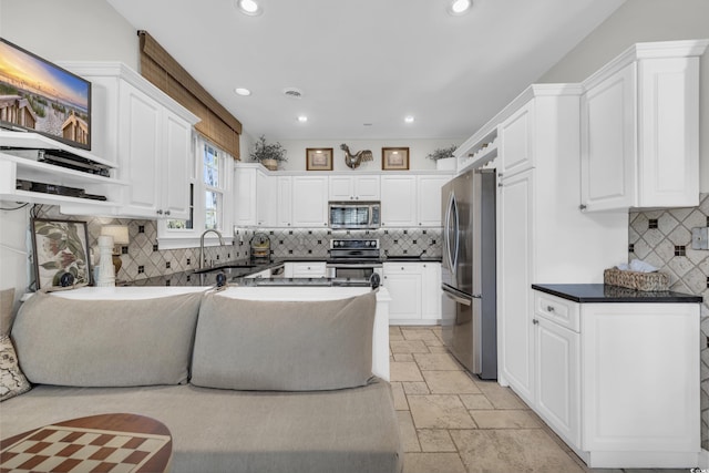 kitchen featuring decorative backsplash, stainless steel appliances, white cabinetry, and sink