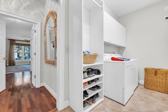 clothes washing area with washer and dryer, cabinets, and light wood-type flooring