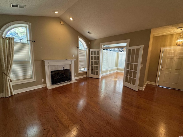 unfurnished living room with wood-type flooring, a textured ceiling, lofted ceiling, and a premium fireplace