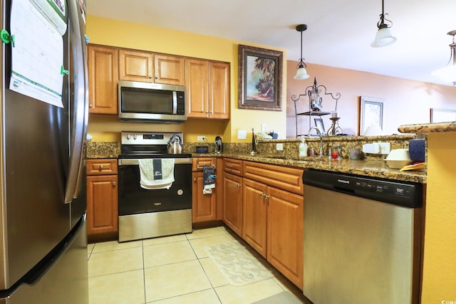 kitchen featuring sink, hanging light fixtures, dark stone countertops, light tile patterned floors, and stainless steel appliances