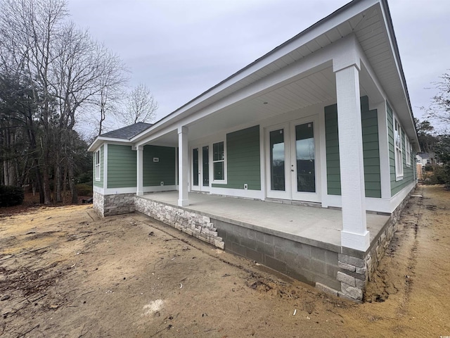 view of side of home featuring covered porch and french doors