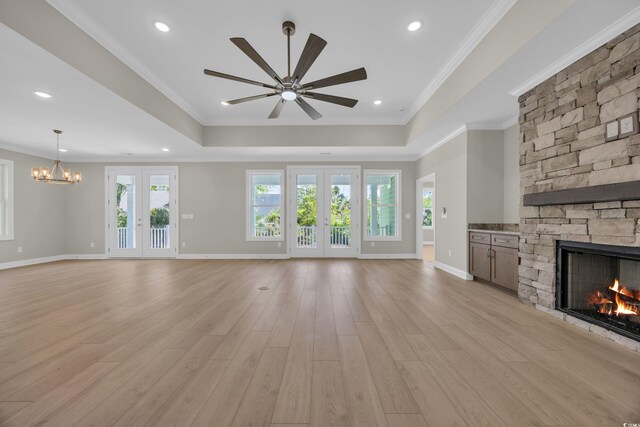 2515 Saint Andrews Dr, Little River, SC 29566 - unfurnished living room featuring a stone fireplace, a tray ceiling, ceiling fan, a chandelier, and ornamental molding