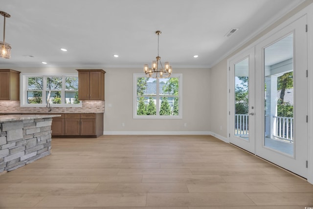 2515 Saint Andrews Dr, Little River, SC 29566 - kitchen with crown molding, plenty of natural light, decorative backsplash, brown cabinets, and recessed lighting