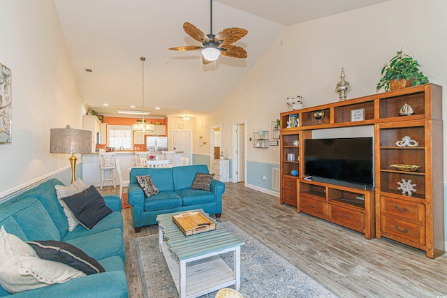 living room featuring ceiling fan, high vaulted ceiling, and light hardwood / wood-style flooring