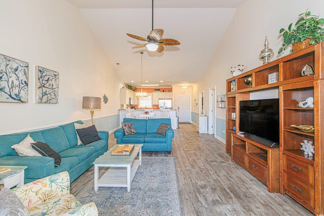 living room with ceiling fan, high vaulted ceiling, and light wood-type flooring