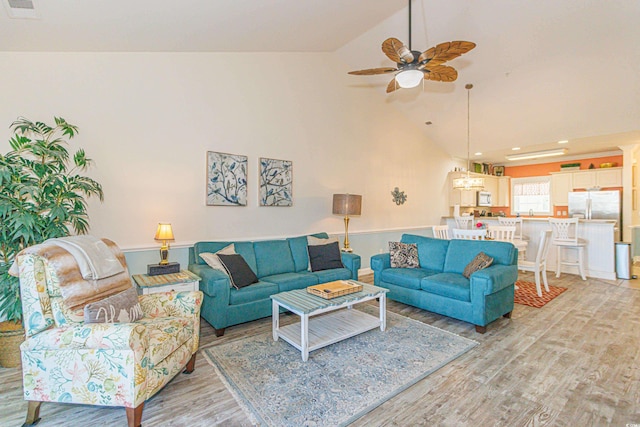 living room with high vaulted ceiling, ceiling fan with notable chandelier, and light wood-type flooring