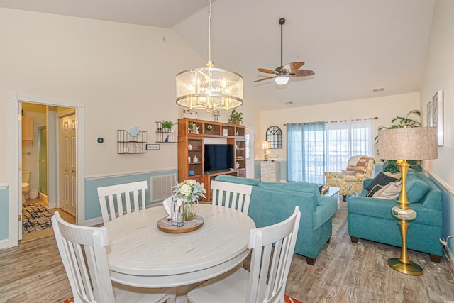 dining space featuring high vaulted ceiling, ceiling fan with notable chandelier, and light hardwood / wood-style floors