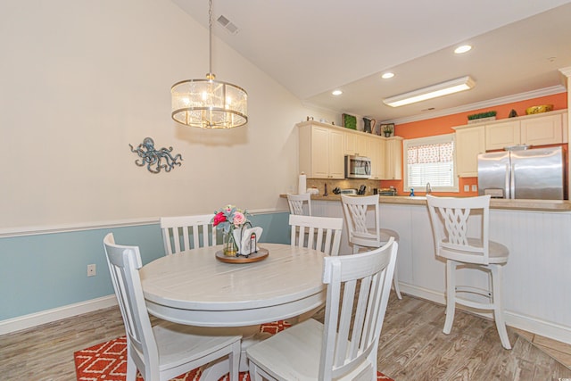 dining area featuring lofted ceiling, ornamental molding, and light hardwood / wood-style floors