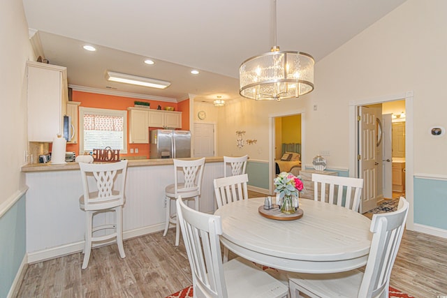 dining space featuring ornamental molding, lofted ceiling, light hardwood / wood-style floors, and a notable chandelier