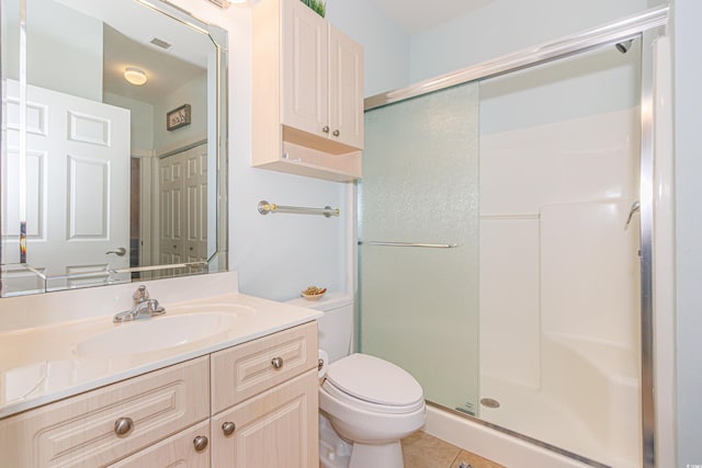 bathroom with vanity, toilet, a shower with shower door, and tile patterned flooring