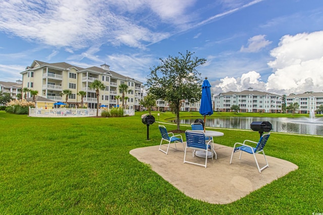 surrounding community featuring a water view, a patio, and a lawn