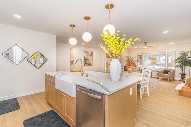 kitchen featuring light stone countertops, stainless steel dishwasher, sink, pendant lighting, and light hardwood / wood-style flooring