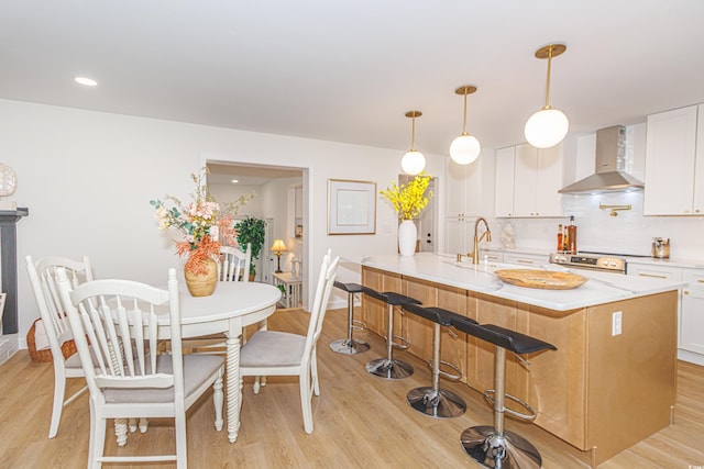 kitchen with light hardwood / wood-style flooring, white cabinetry, and wall chimney exhaust hood