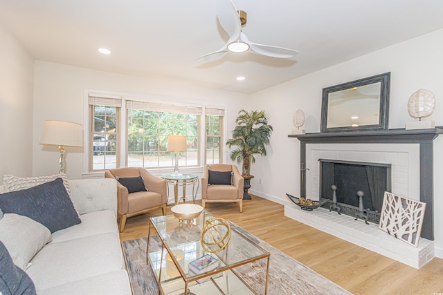 living room featuring hardwood / wood-style floors, a brick fireplace, ceiling fan, and a healthy amount of sunlight