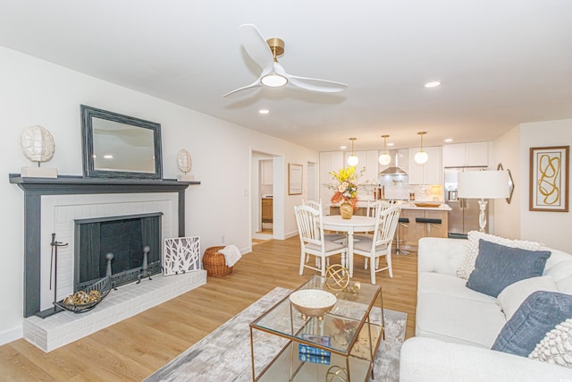 living room with a fireplace, light hardwood / wood-style floors, and ceiling fan