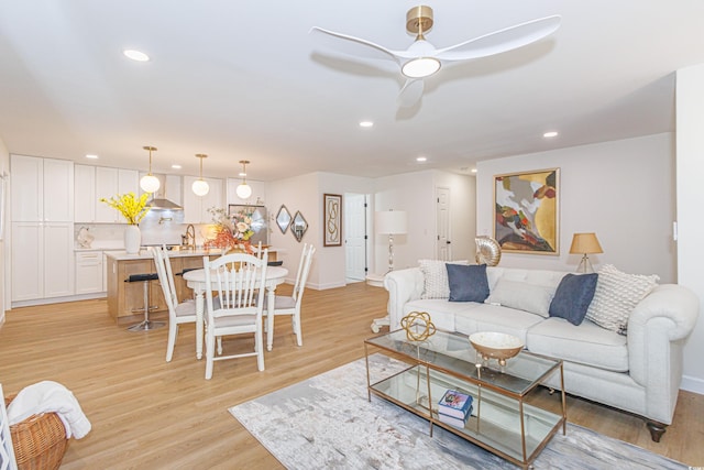 living room with ceiling fan, light hardwood / wood-style floors, and sink