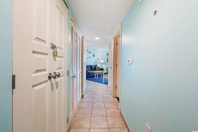 hall with light tile patterned floors and a textured ceiling