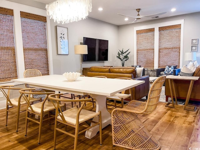 dining room featuring ceiling fan with notable chandelier and wood-type flooring