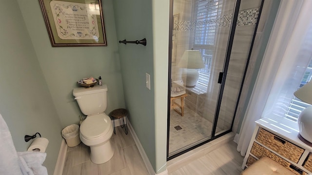 bathroom with tile patterned flooring, a shower with shower door, and toilet