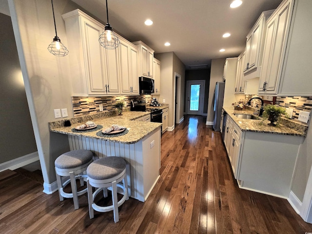 kitchen with appliances with stainless steel finishes, dark hardwood / wood-style flooring, sink, decorative light fixtures, and white cabinets