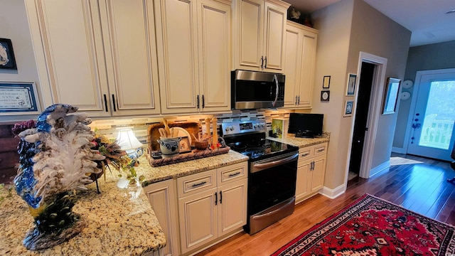 kitchen featuring light stone countertops, appliances with stainless steel finishes, tasteful backsplash, and light hardwood / wood-style flooring