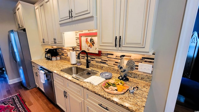 kitchen with light stone countertops, appliances with stainless steel finishes, dark hardwood / wood-style flooring, sink, and white cabinets