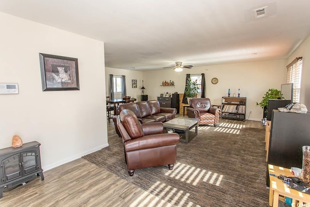 living room featuring a wood stove, ceiling fan, and hardwood / wood-style flooring