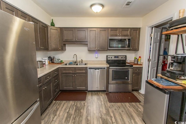 kitchen featuring sink, dark wood-type flooring, dark brown cabinets, and appliances with stainless steel finishes