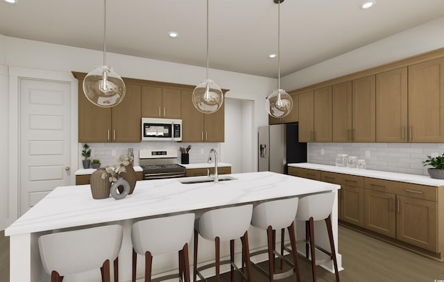 kitchen featuring hanging light fixtures, appliances with stainless steel finishes, sink, tasteful backsplash, and a center island with sink