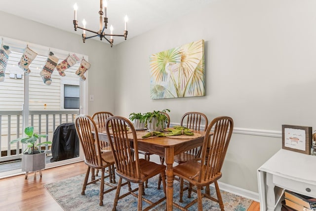 dining space with hardwood / wood-style floors and a notable chandelier