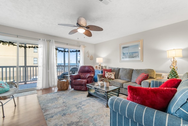 living room with ceiling fan, light hardwood / wood-style flooring, and a textured ceiling