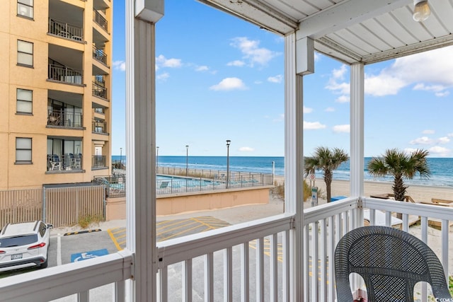 sunroom / solarium with plenty of natural light, a water view, and a beach view